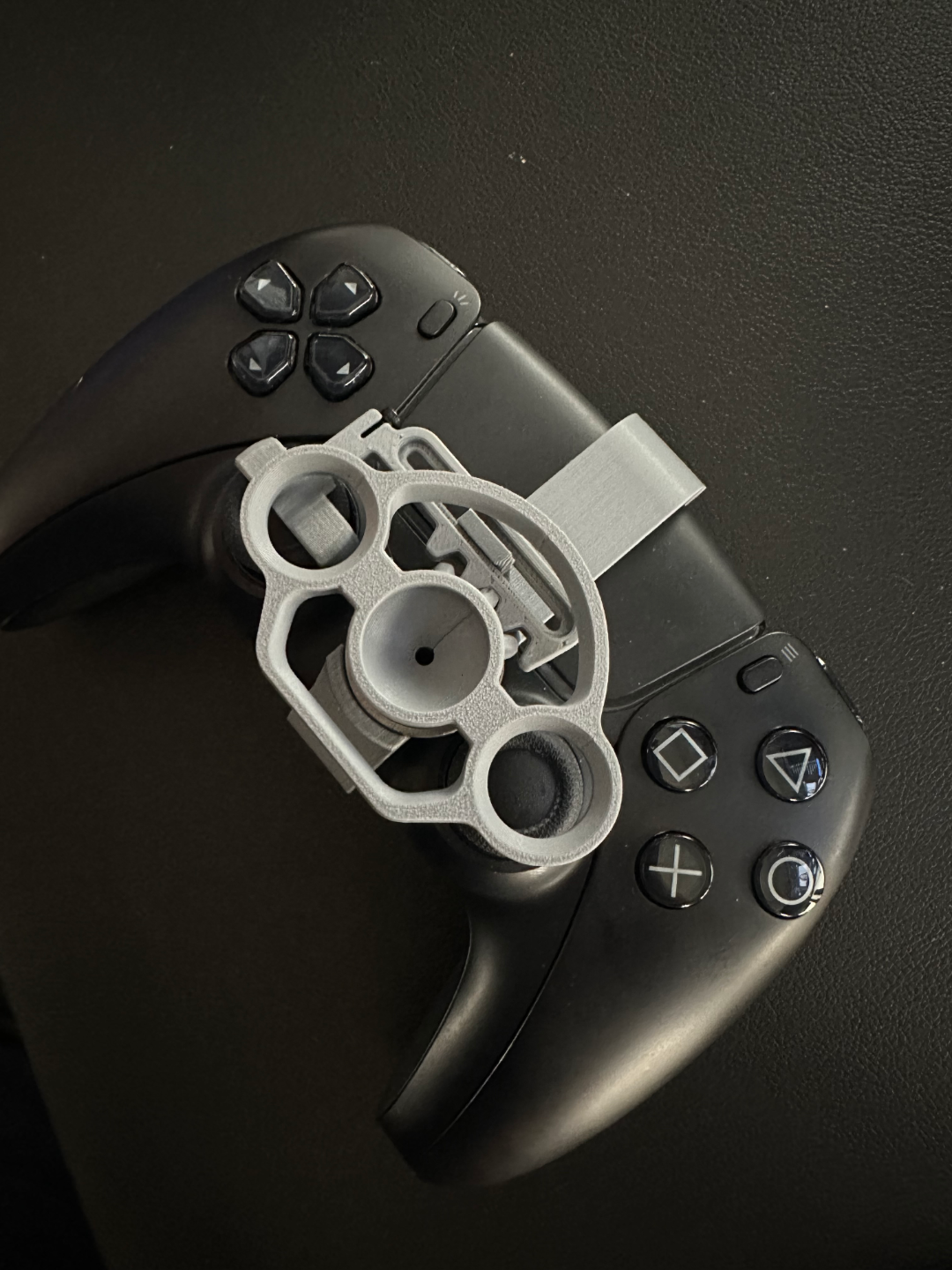 PlayStation DualSense with grey 3D-printed mini steering wheel mod on the touchpad