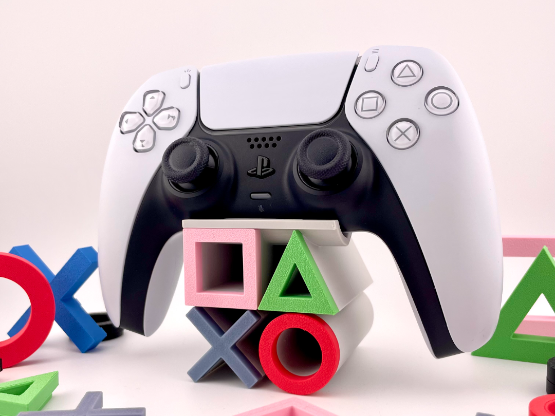DualSense on a stand with large colorful PlayStation triangle circle cross square symbols as supports