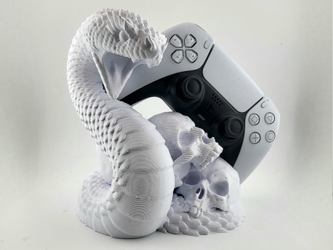 White 3D-printed snake and skull stand holding a black and white DualSense controller