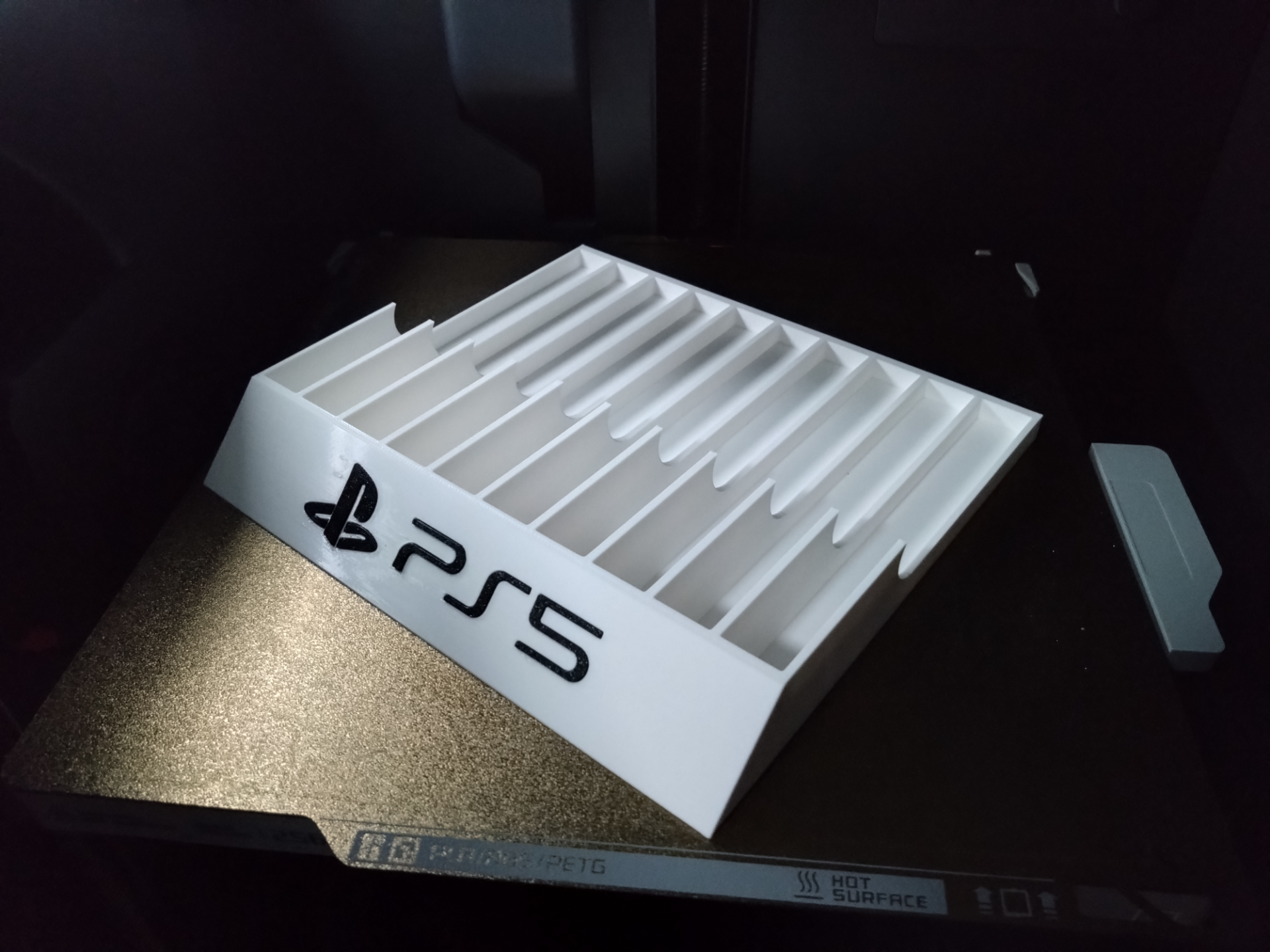 White 3D-printed PlayStation 5 game case holder with ten slots and PS5 branding on the front